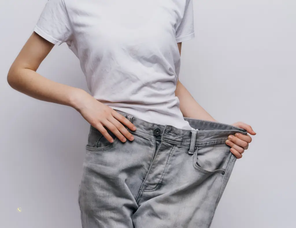 Person showing oversized jeans for weight loss.
